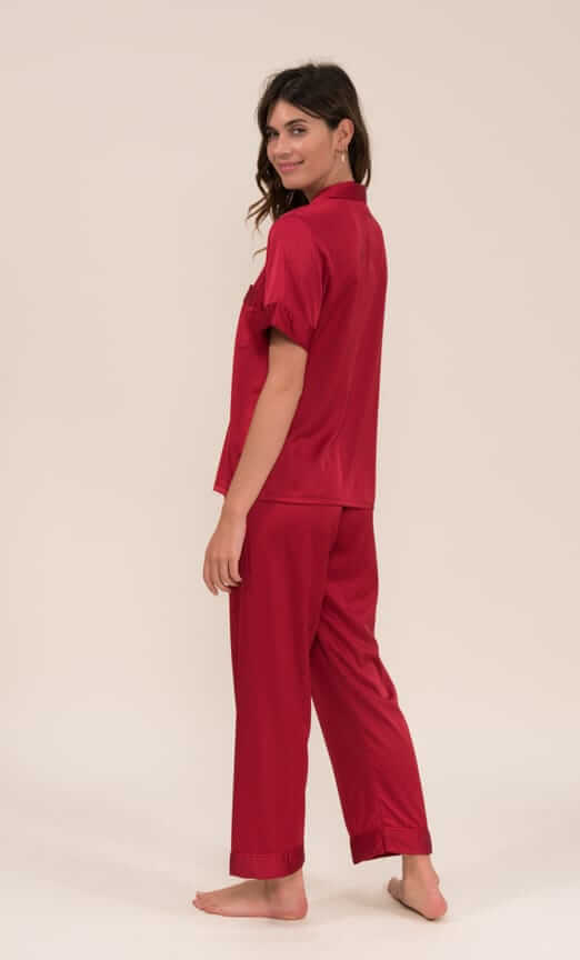 Woman wearing a short-sleeve satin pajama set in bordeaux, featuring lightweight stretch fabric made of 97% polyester and 3% elastane.