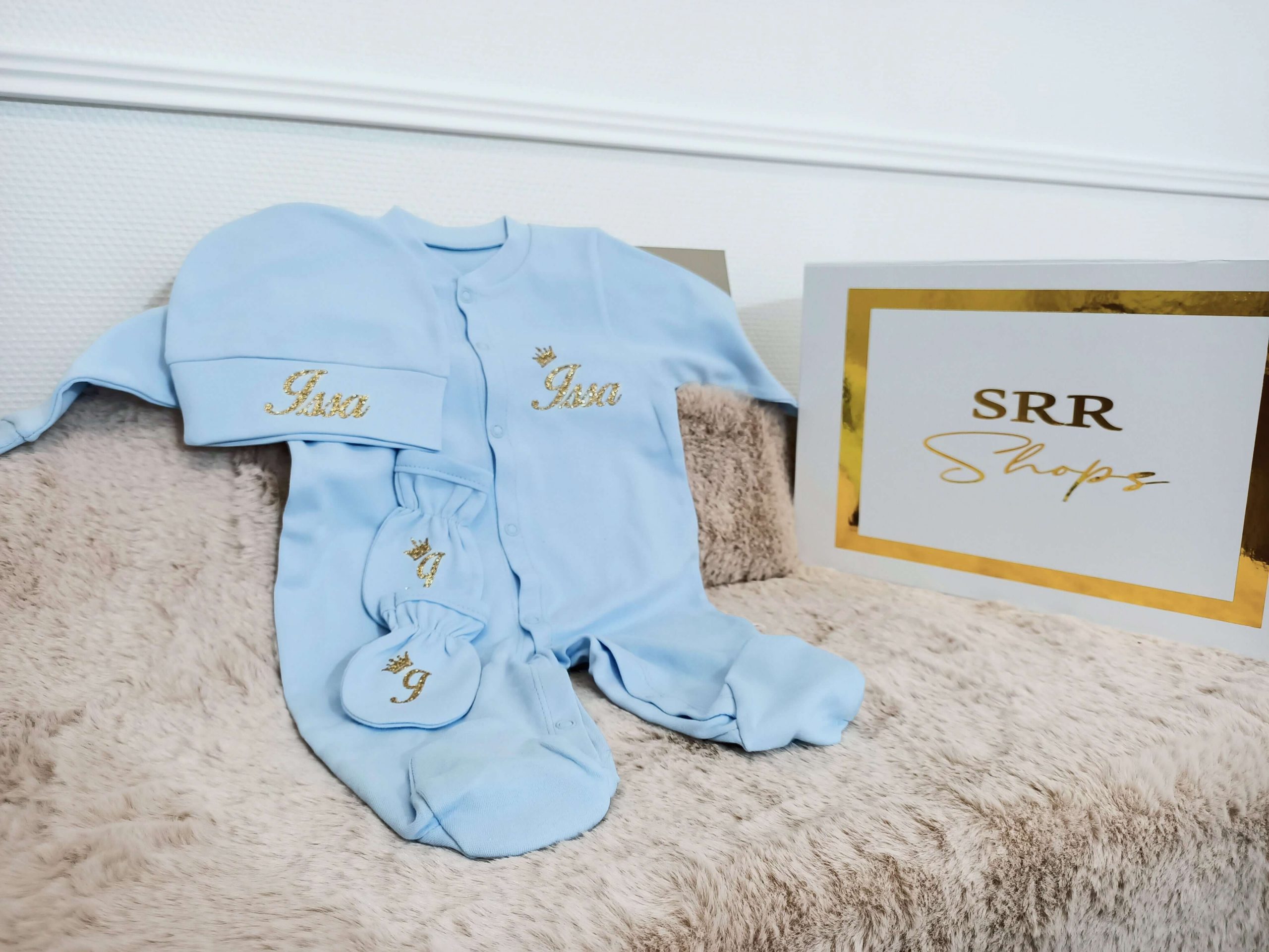 Personnalisé pyjamas bébé bleu avec nom en doré sur un fond moelleux avec boîte de cadeau SRR Shops.